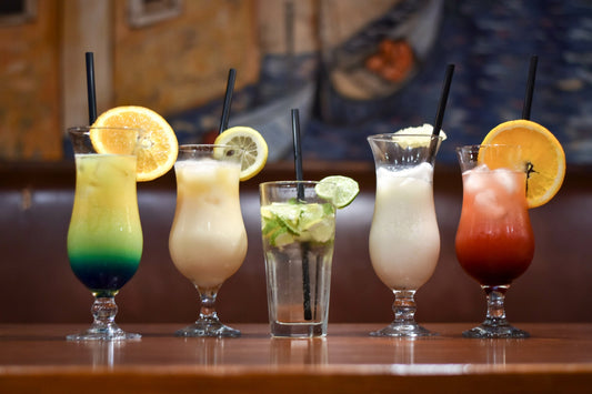 Summer coctails in the table. PiΓ±a Colada with pineapple slice, Blue lagoon, mojito with lime and mint, creamy coctail, tequila sunrise with orange