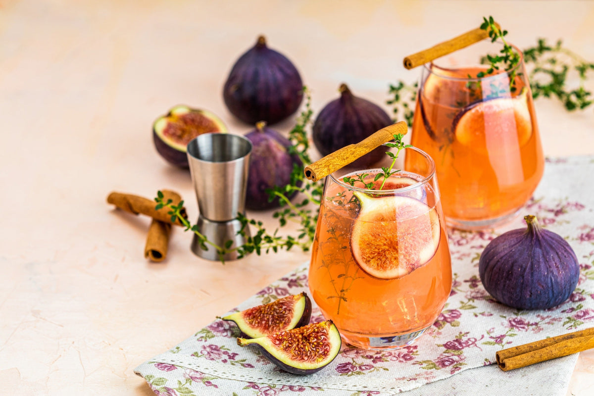Pink cocktail with fig, thyme and ice in glass