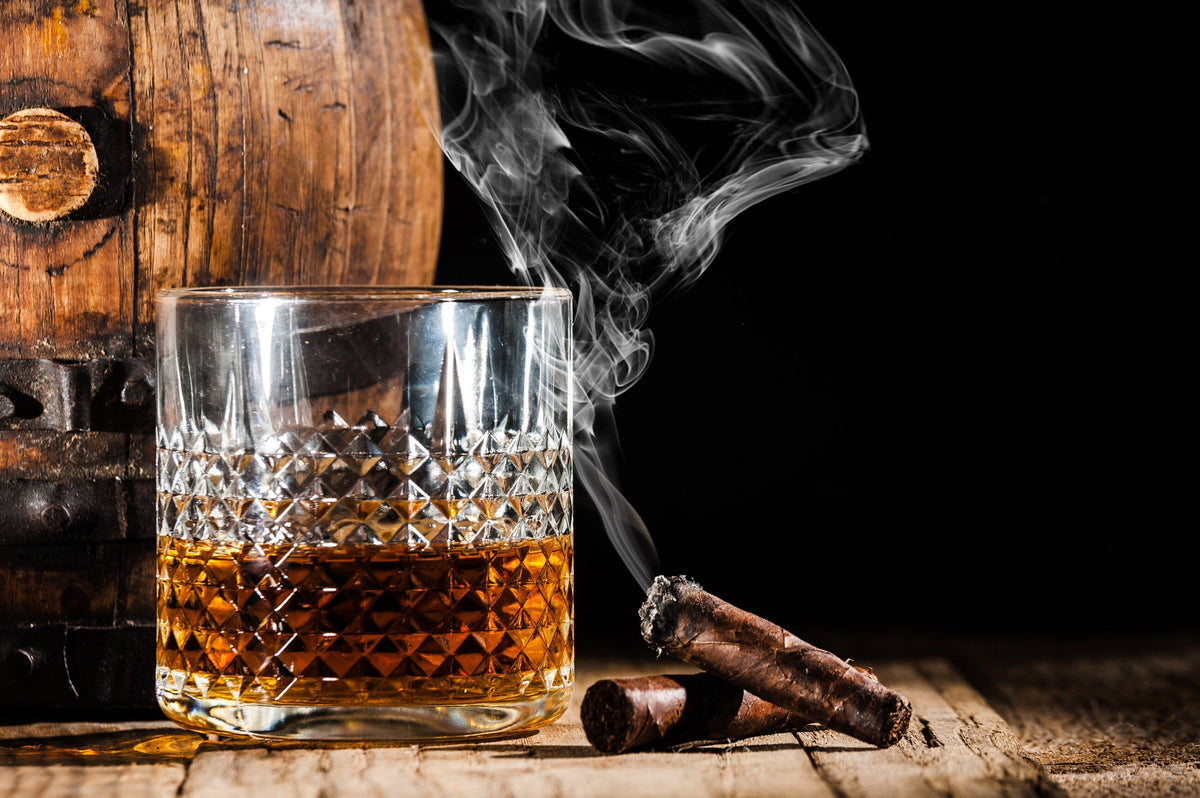 Glass of alcohol and smoking noble cigar on a black background