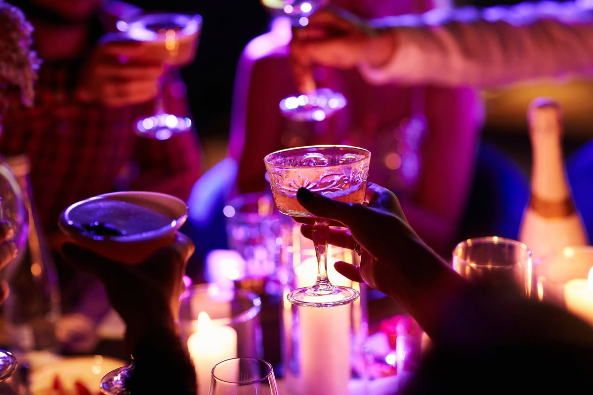 Close up of people drinking cocktails in restaurant. People having good time, cheering and drinking cold cocktails, enjoying friendship together in restaurant, close up view on hands